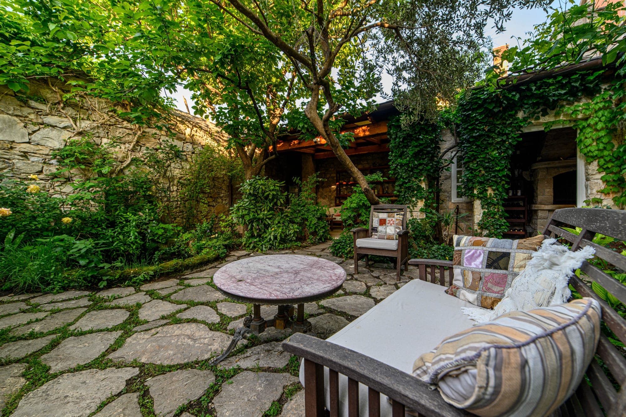 Vrt Wine Garden Skradin noću s upaljenim svjećicama i bujnim zelenilom oko ribnjaka